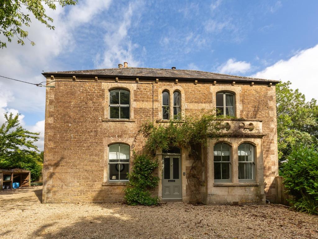 una vieja casa de ladrillo con una puerta en un campo en Vallis Oak Villa, en Frome