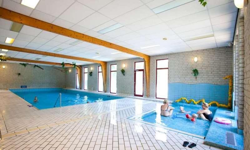 twee kinderen spelen in een groot zwembad bij Holiday Home Maridu Wellness in Arnhem