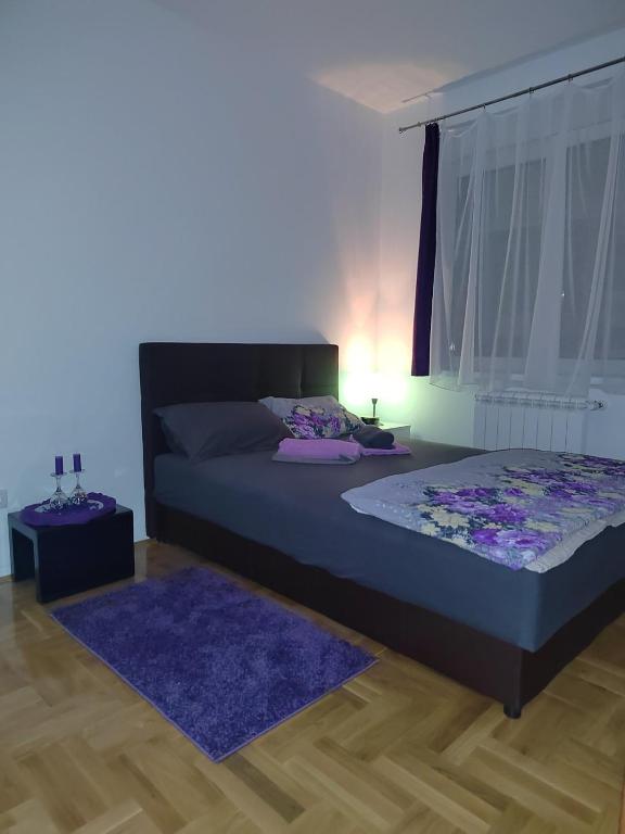 a bedroom with a bed and a purple rug at Apartman Mančić in Pirot