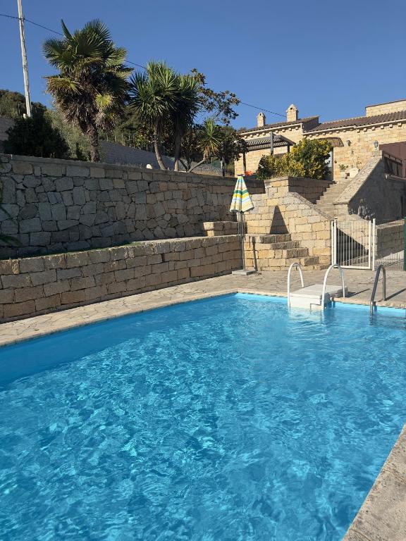 une grande piscine bleue avec un mur en briques dans l'établissement Villa Campana - Sartène, à Sartène