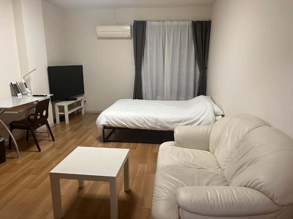 een woonkamer met een bank en een bed bij Roxy inn in Oita