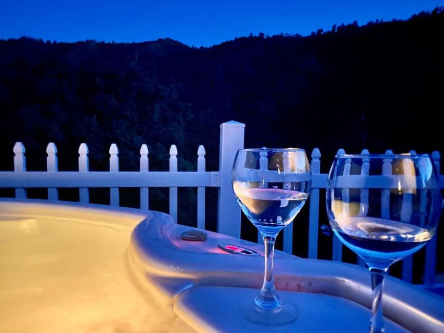 two wine glasses sitting on a table next to a tub at Happy Hedgehog River Views Hot Tub Private in Ahwahnee