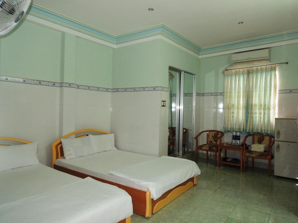 a bedroom with two beds and a table and a chair at Kathy Hotel in Phan Thiet