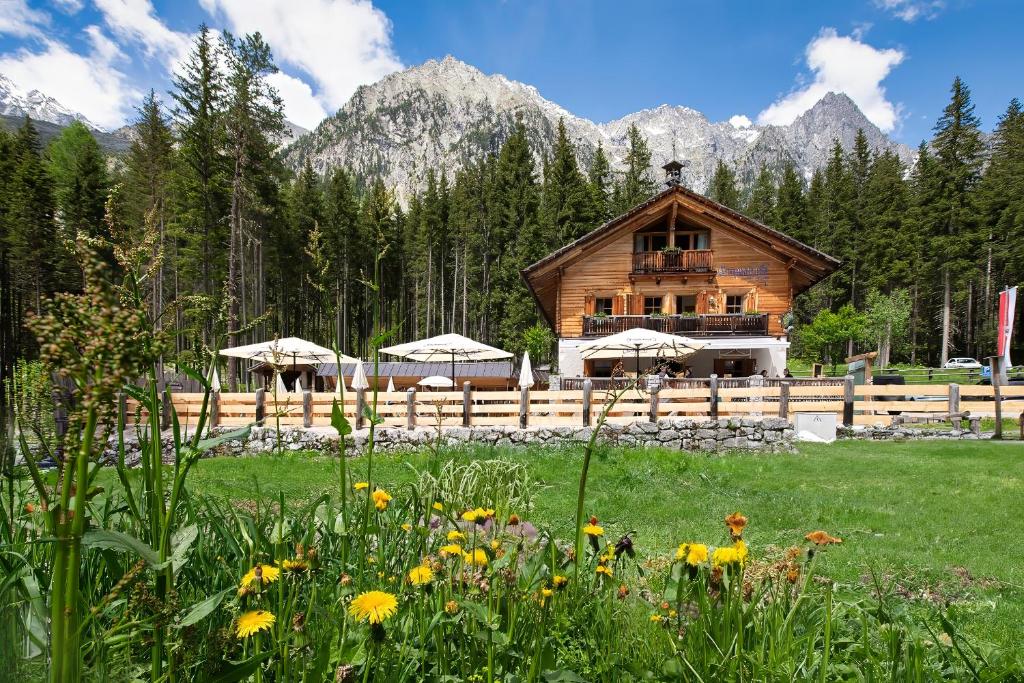 uma cabana de madeira nas montanhas com um campo de flores em Enzianhütte em San Giuseppe in Anterselva