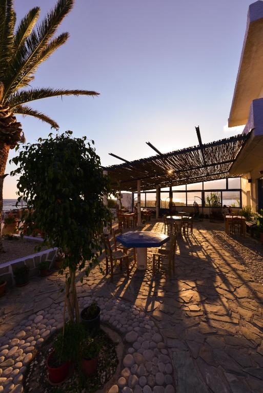a patio with tables and chairs and a palm tree at Coral in Frangokastello