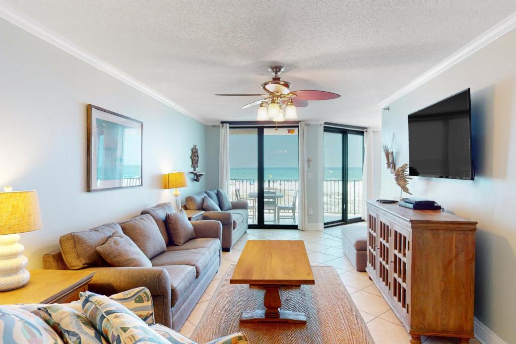 a living room with a couch and a flat screen tv at Phoenix East II 2022 in Orange Beach