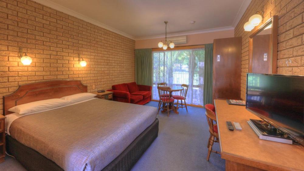 um quarto de hotel com uma cama e uma televisão em Barrass's John Bright Motor Inn em Bright