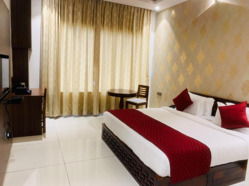 a hotel room with a bed and a table in it at Rajathadri Royal Inn in Bangalore