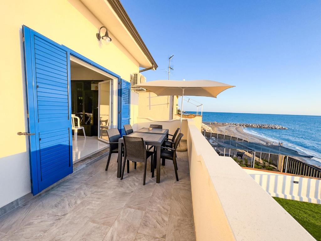 d'un balcon avec une table et des chaises donnant sur l'océan. dans l'établissement Appartamento Fronte Spiaggia con Terrazza Vista Mare, à Bonifati