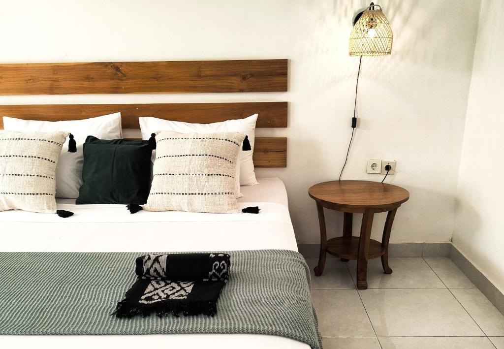 a bedroom with a bed and a table with a lamp at Amel House in Gili Air