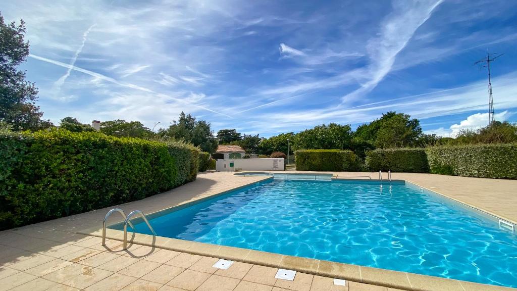 una grande piscina in un cortile con cespugli di Petite location dans résidence avec piscine et terrains de tennis a La Couarde-sur-Mer