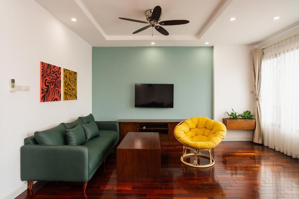 a living room with a green couch and a yellow stool at ALEAH HOME in Hanoi