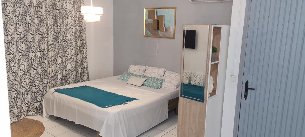 een kleine slaapkamer met een bed met witte lakens en blauwe kussens bij Paradies Caraïbes III in Les Abymes