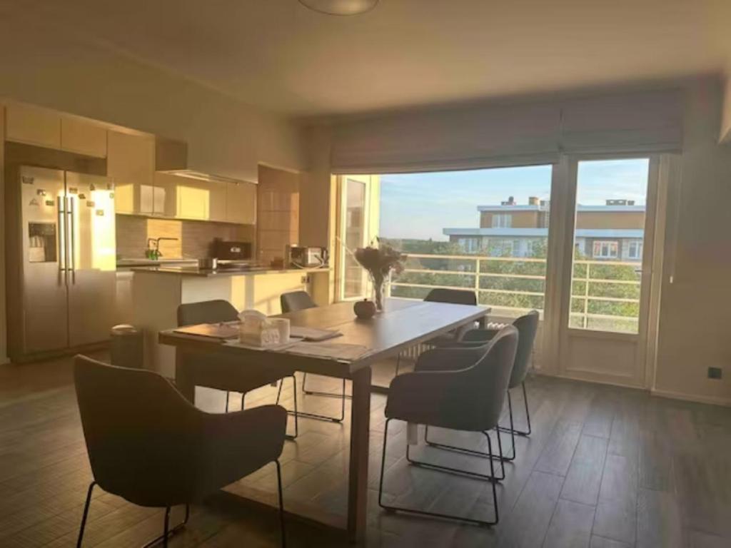 une cuisine avec une table et des chaises ainsi qu'une grande fenêtre dans l'établissement Clam，grand apartment in Uccle, à Bruxelles