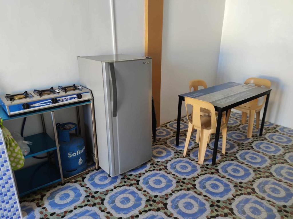 La cuisine est équipée d'une table et d'un réfrigérateur en acier inoxydable. dans l'établissement Jacky rental house, à Calape
