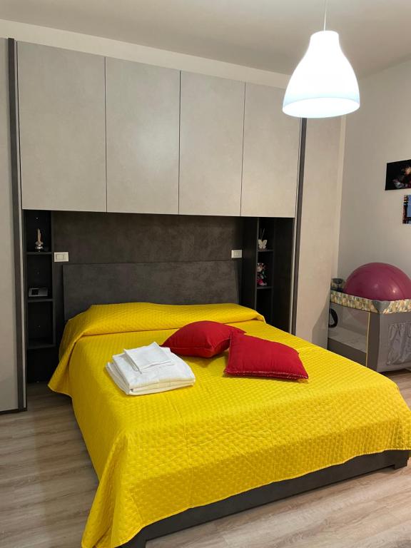 Una cama amarilla con dos almohadas rojas. en Nuova Casa di Mattia Bologna en Bolonia