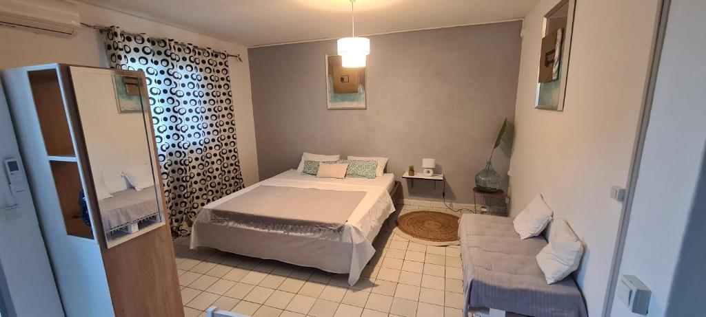 a small bedroom with a bed and a couch at Paradies Caraïbes I in Les Abymes