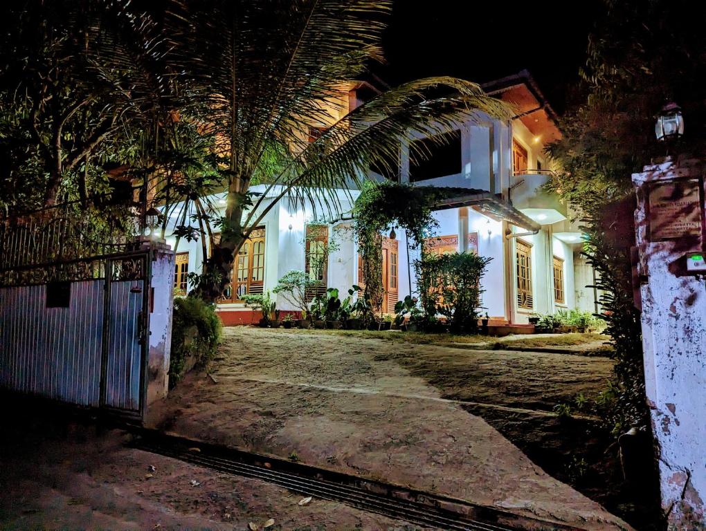 a house with a gate and palm trees at night at Moon Water's Edge in Kandy