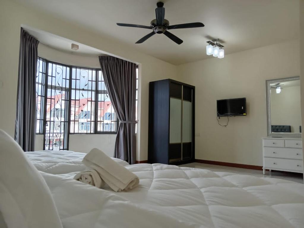- une chambre avec un grand lit blanc et un ventilateur de plafond dans l'établissement BUTTERWORTH RAJA UDA RAYA HOMESTAY, à Butterworth