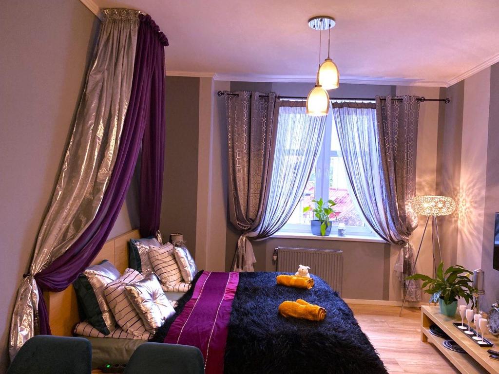 um quarto com uma cama com cortinas roxas e uma janela em Silwer ROOM em Cracóvia