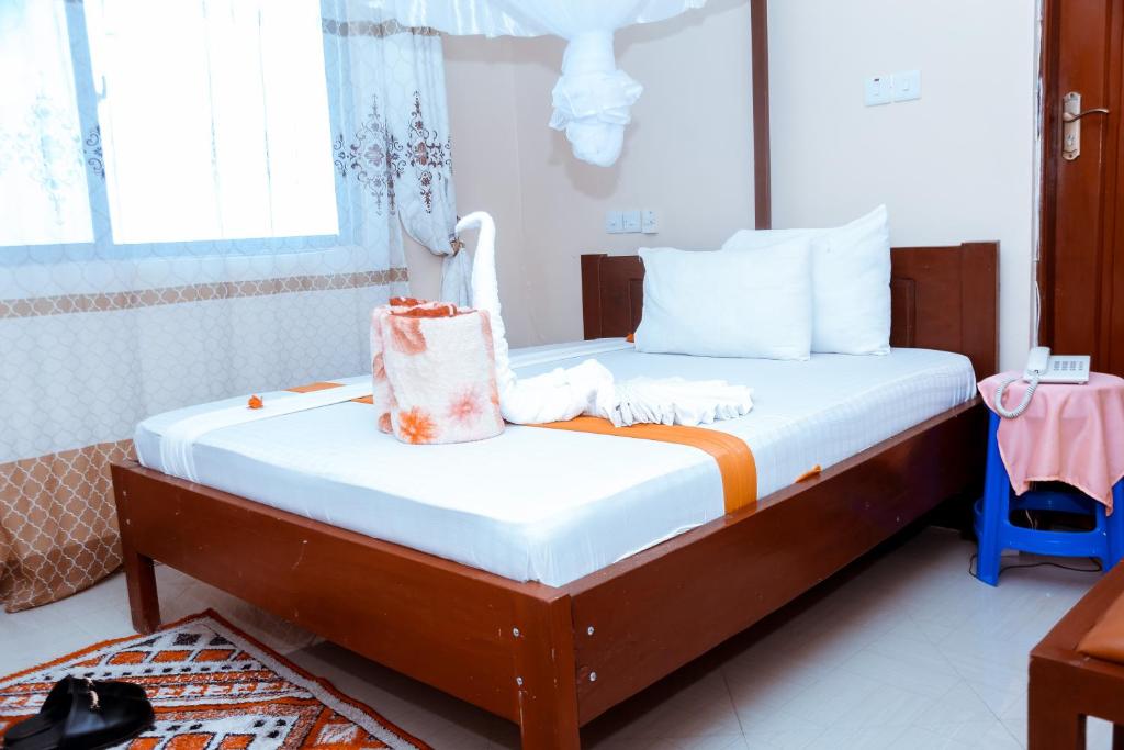 a small bedroom with a bed with white sheets at Port Park Hotel in Mwanza