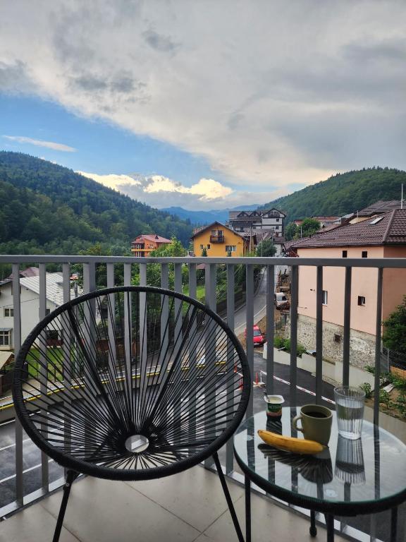 Una silla en un balcón con vista a una ciudad. en Large Studio - 4 Guests - Balcony - Free Parking, en Sinaia
