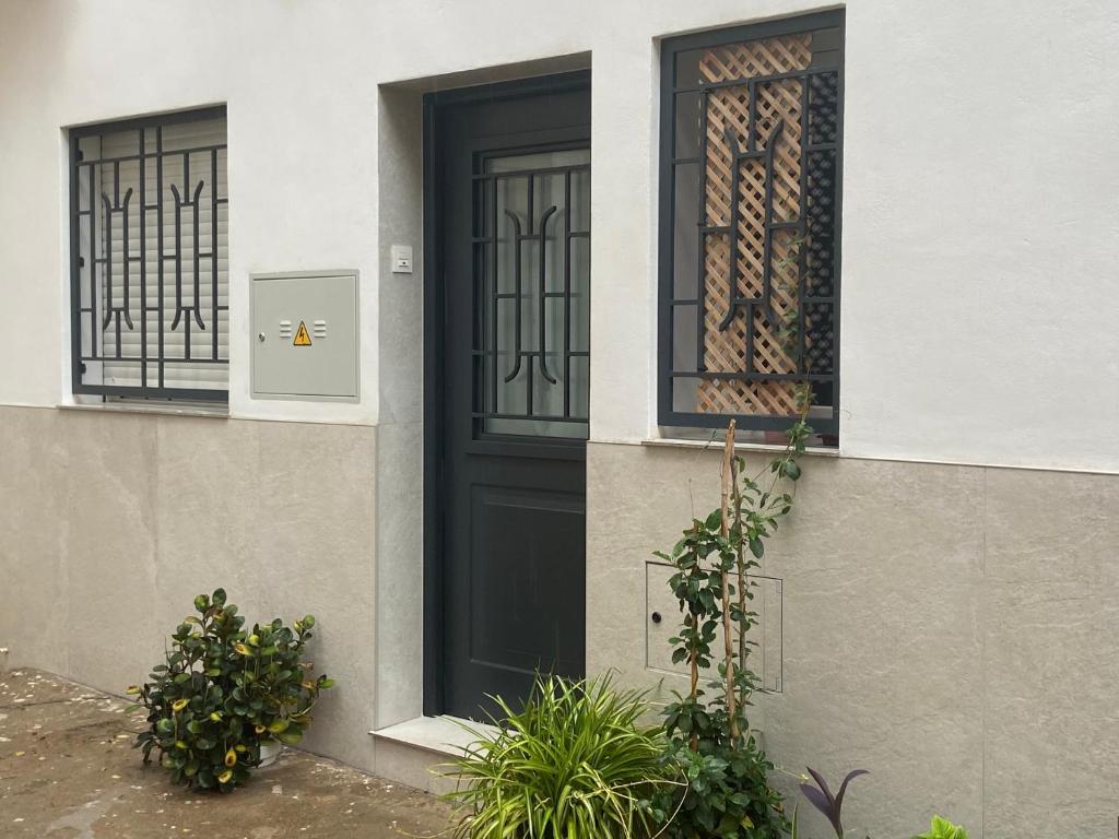 eine schwarze Tür an einem Haus mit zwei Fenstern in der Unterkunft Apartamento La Mamola in La Mamola