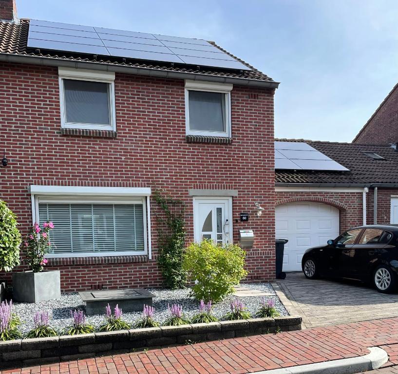 een rood bakstenen huis met zonnepanelen op het dak bij Zuid-Limburg B&B OpdeBossen in Eygelshoven