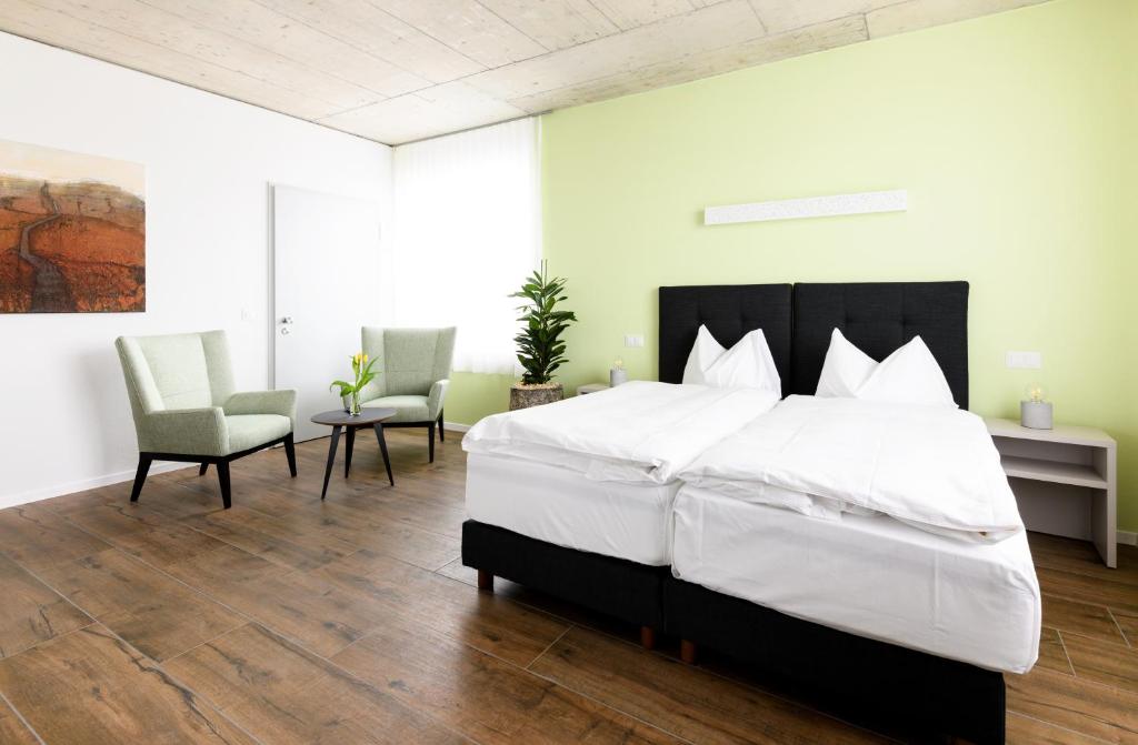 a bedroom with a large bed and two chairs at Partner Hotel AG Zofingen in Zofingen