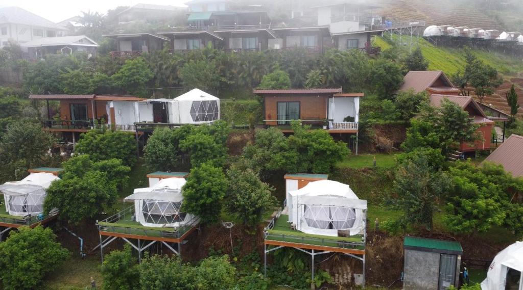 Phu Fahsai Homestay في Mon Jam: مجموعة منازل على تلة فيها اشجار