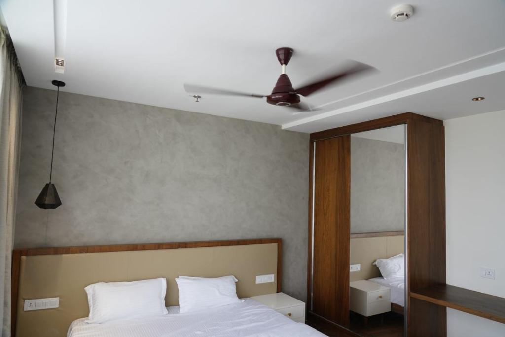 Royal Convention center في Pattāmbi: غرفة نوم مع سرير مع مروحة سقف ومرآة