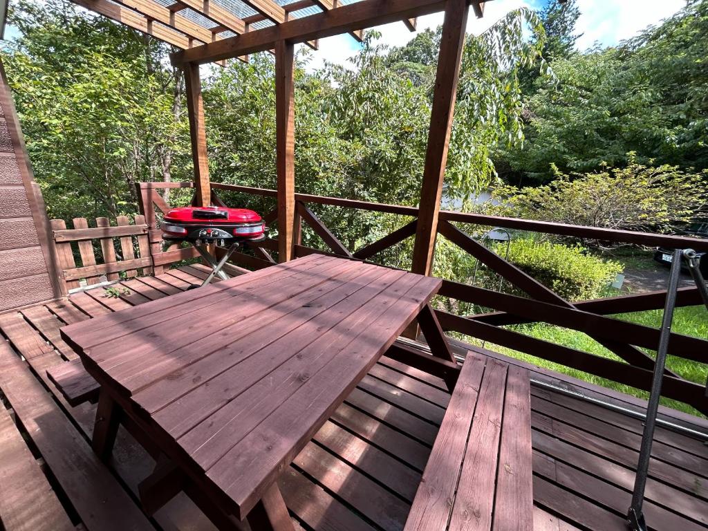 a wooden deck with a picnic table and a grill at フォレストハウス伊豆箱根 in Kannami