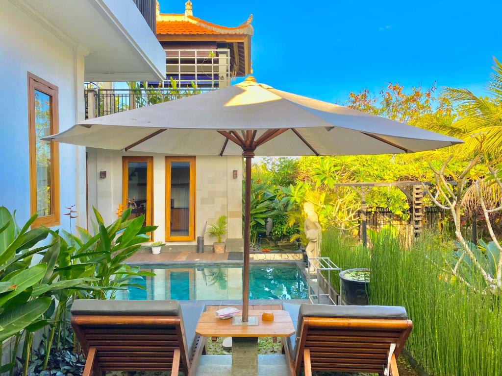 a table with an umbrella next to a swimming pool at Mandox Villa Bali in Ungasan