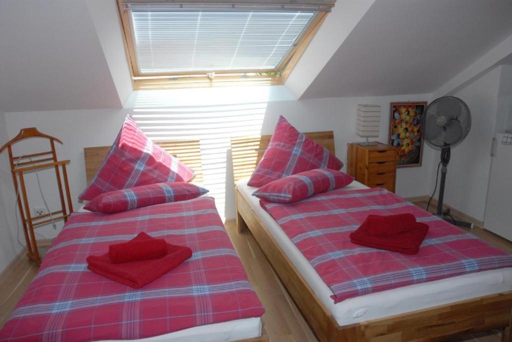 two beds with red pillows in a room at Klosterherberge Economy in Meßkirch