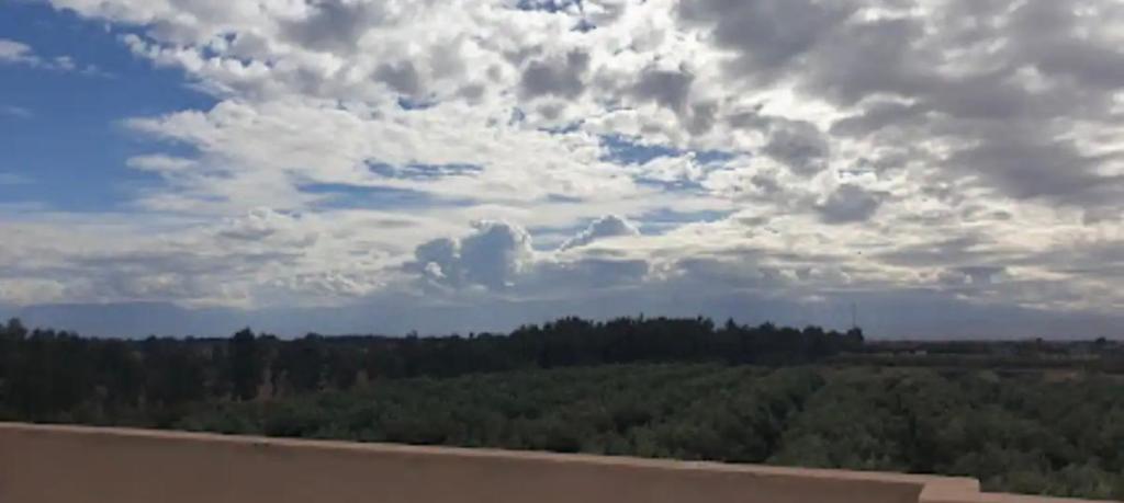 een uitzicht op een veld met bomen onder een bewolkte hemel bij Parfaite appartement en résidence in Marrakesh