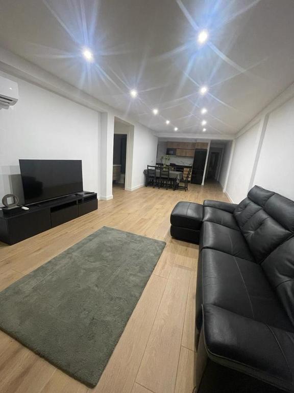 a living room with a black couch and a flat screen tv at UIM Mediterraneo Conqueridor Wifi in Sagunto
