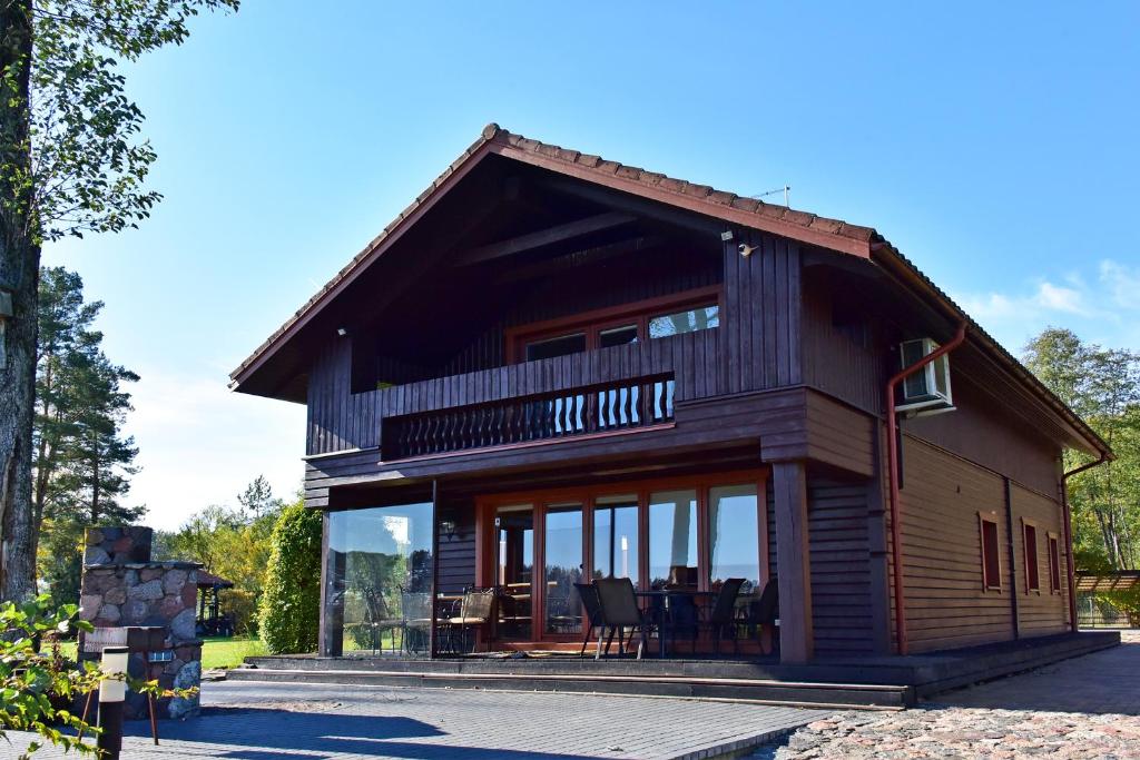 a wooden house with glass doors and windows at Bebrusų sodyba in Molėtai