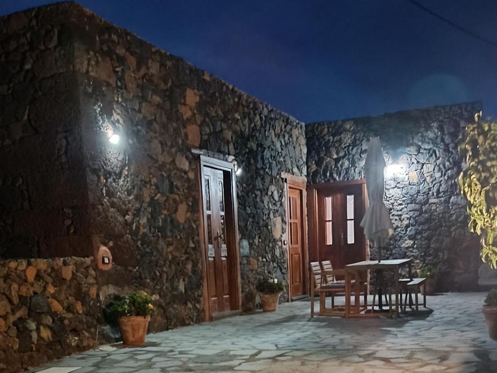 Casa Rural LUCÍA في Isora: مبنى حجري مع طاولة وكراسي على فناء