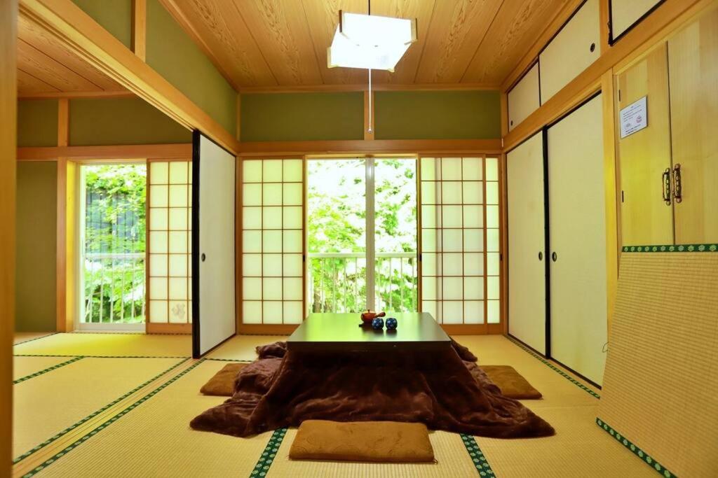 a room with a table in the middle of a room with windows at FOREST HOUSE NIKKO in Nikko