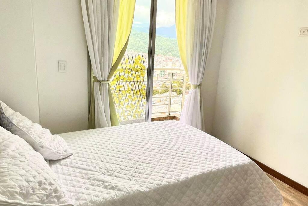ein Schlafzimmer mit einem weißen Bett und einem Fenster in der Unterkunft Av santander Apartaestudio premium in Manizales