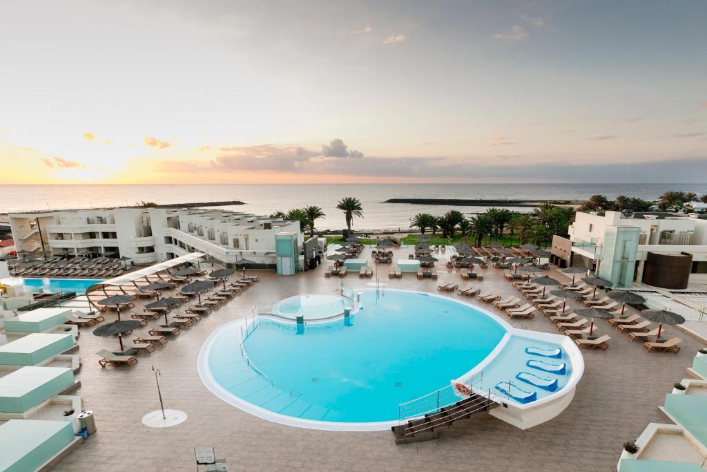 eine Luftansicht eines Resorts mit Pool und Stühlen in der Unterkunft HD Beach Resort in Costa Teguise