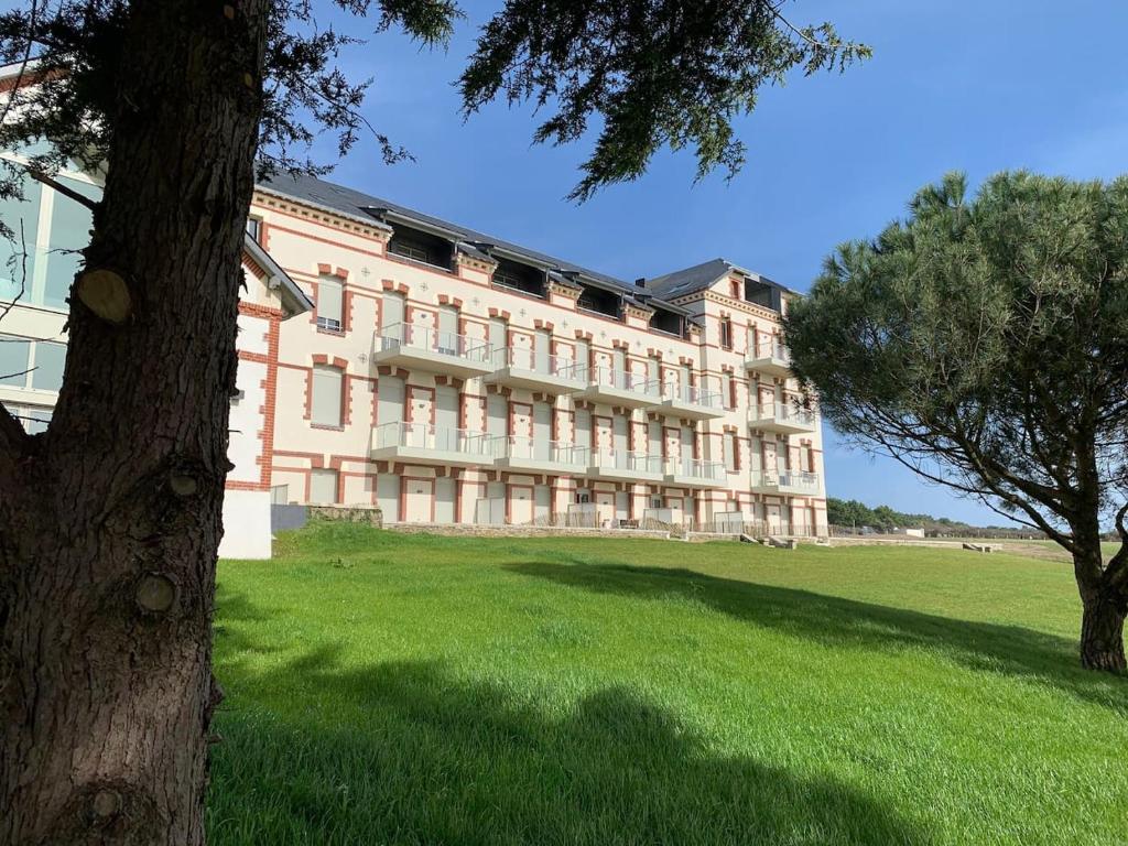 un grand bâtiment avec un arbre devant dans l'établissement Appartement T2 de standing face mer Pornic, à Pornic