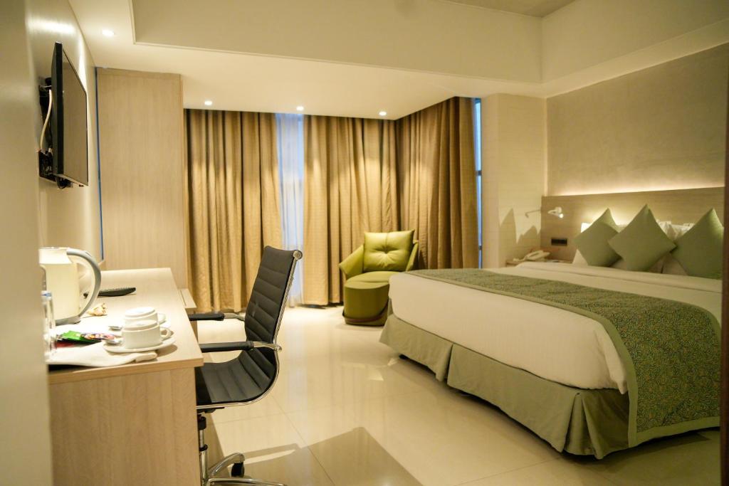 ein Hotelzimmer mit einem großen Bett und einem Schreibtisch in der Unterkunft Lakeshore Heights in Dhaka