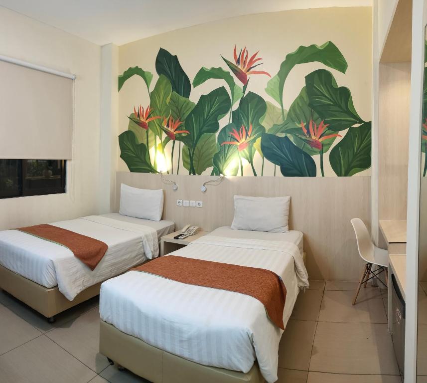 two beds in a room with a painting on the wall at D'Bamboo Suites in Jakarta