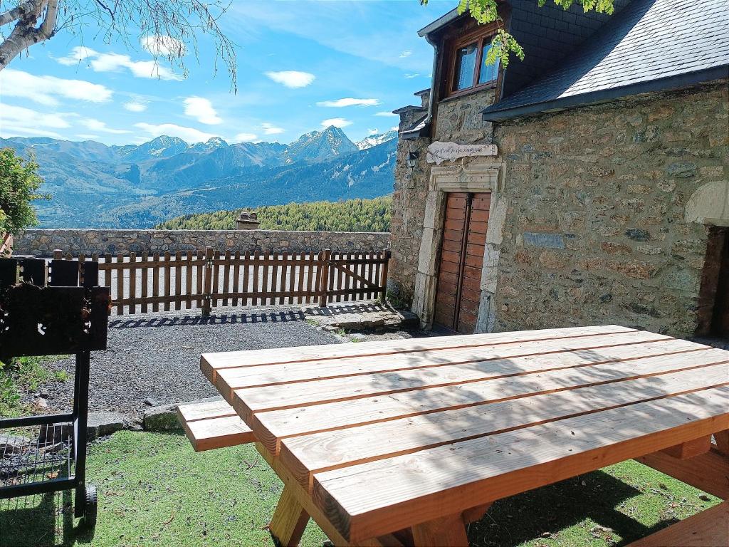 una mesa de picnic de madera sentada fuera de un edificio en La grange du hameau, en Saint-Lary-Soulan