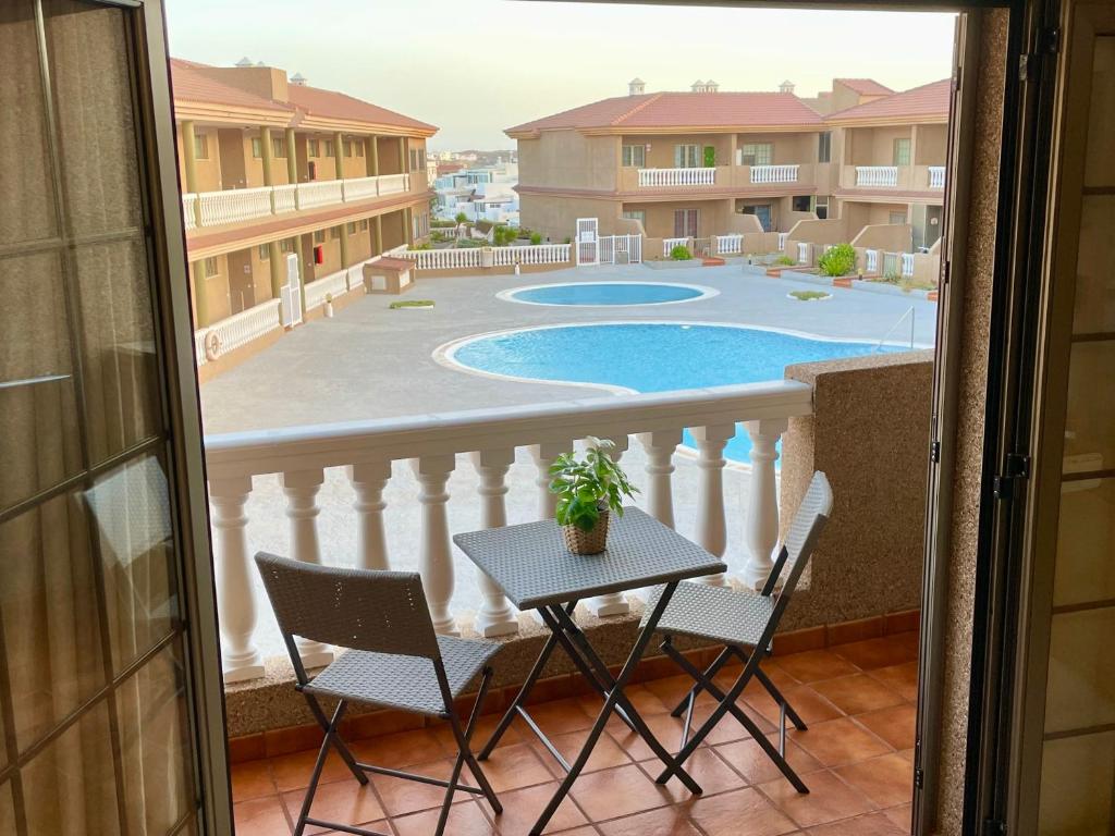 einen Balkon mit einem Tisch, Stühlen und einem Pool in der Unterkunft Apartamento Dulce Vista in Poris de Abona