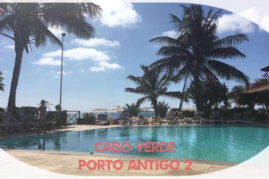 een zwembad met palmbomen en een bord met de titel "cape verde portal antico" bij Porto Antigo 2 Beach Club in Santa Maria