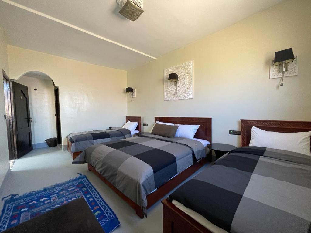 1 dormitorio con 2 camas y alfombra azul en Tizi Maison d'Hôtes, en Telouet