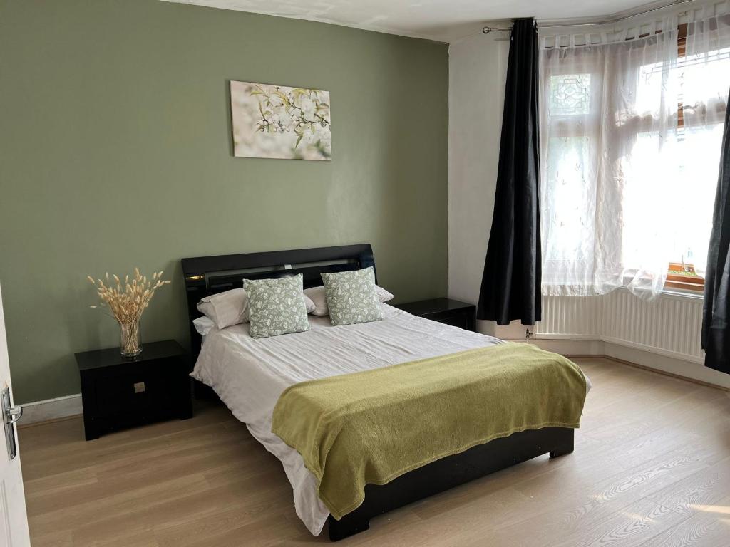 a bedroom with a large bed with green walls at The Leyton Oasis in London