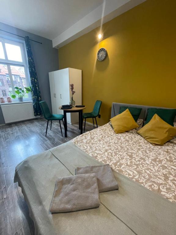 ein Schlafzimmer mit einem Bett mit gelben Wänden und grünen Stühlen in der Unterkunft Apartament Kościuszko in Kattowitz